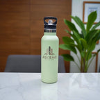 Close-up of engraved company logo on matte sage stainless steel bottle with flip valve lid.