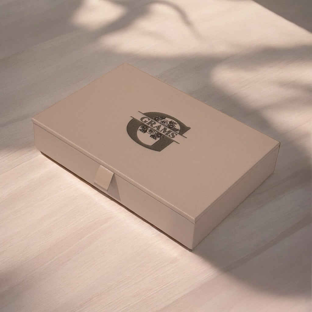 Close-up of engraved initials on taupe jewellery box lid, highlighting detail and texture.