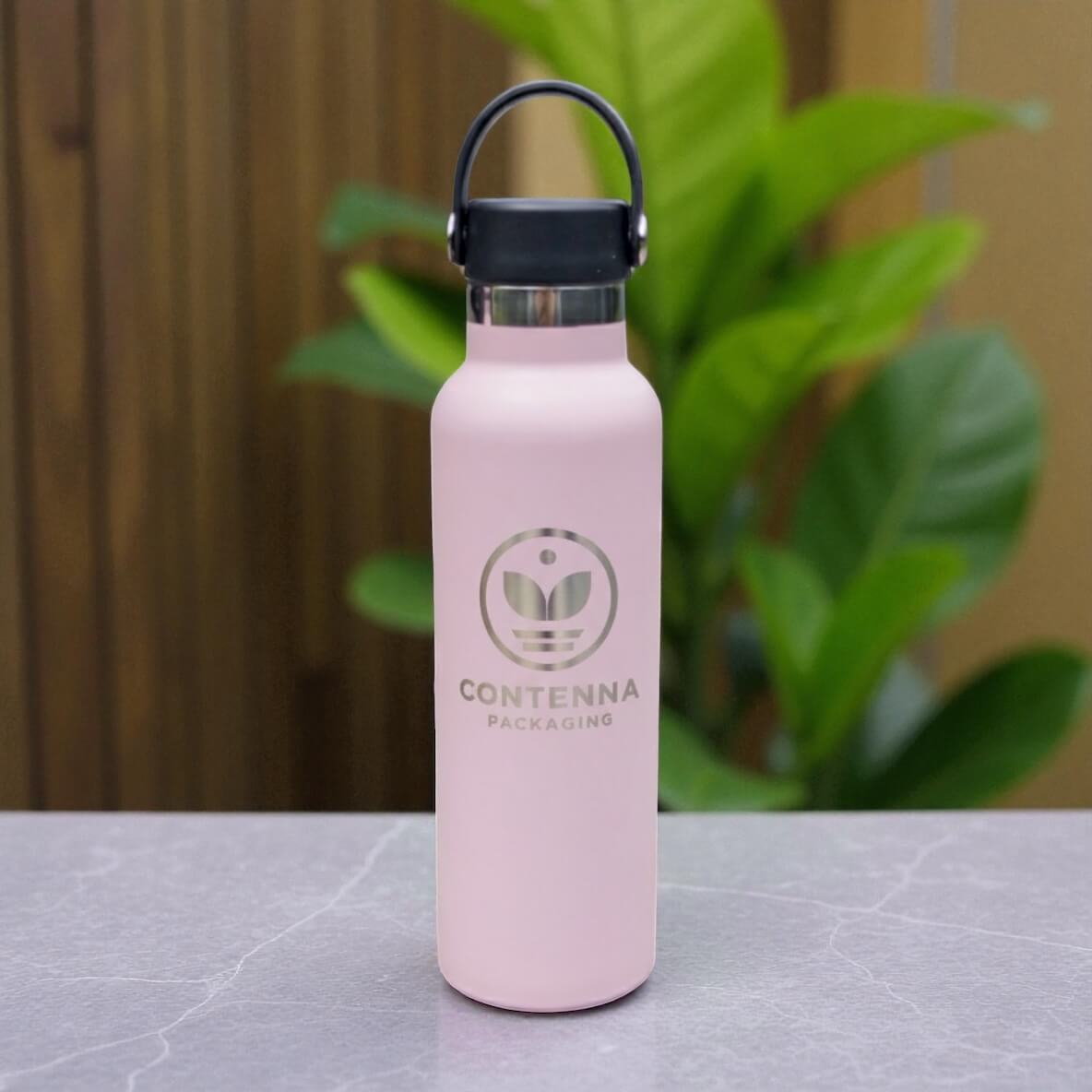 Close-up of engraved logo on matte pink powder-coated bottle with stainless neck detail.