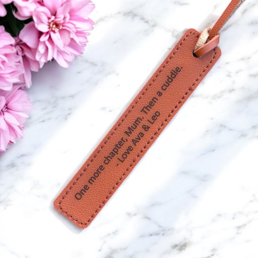 Close-up of engraved message on PU leather bookmark with stitched edges.