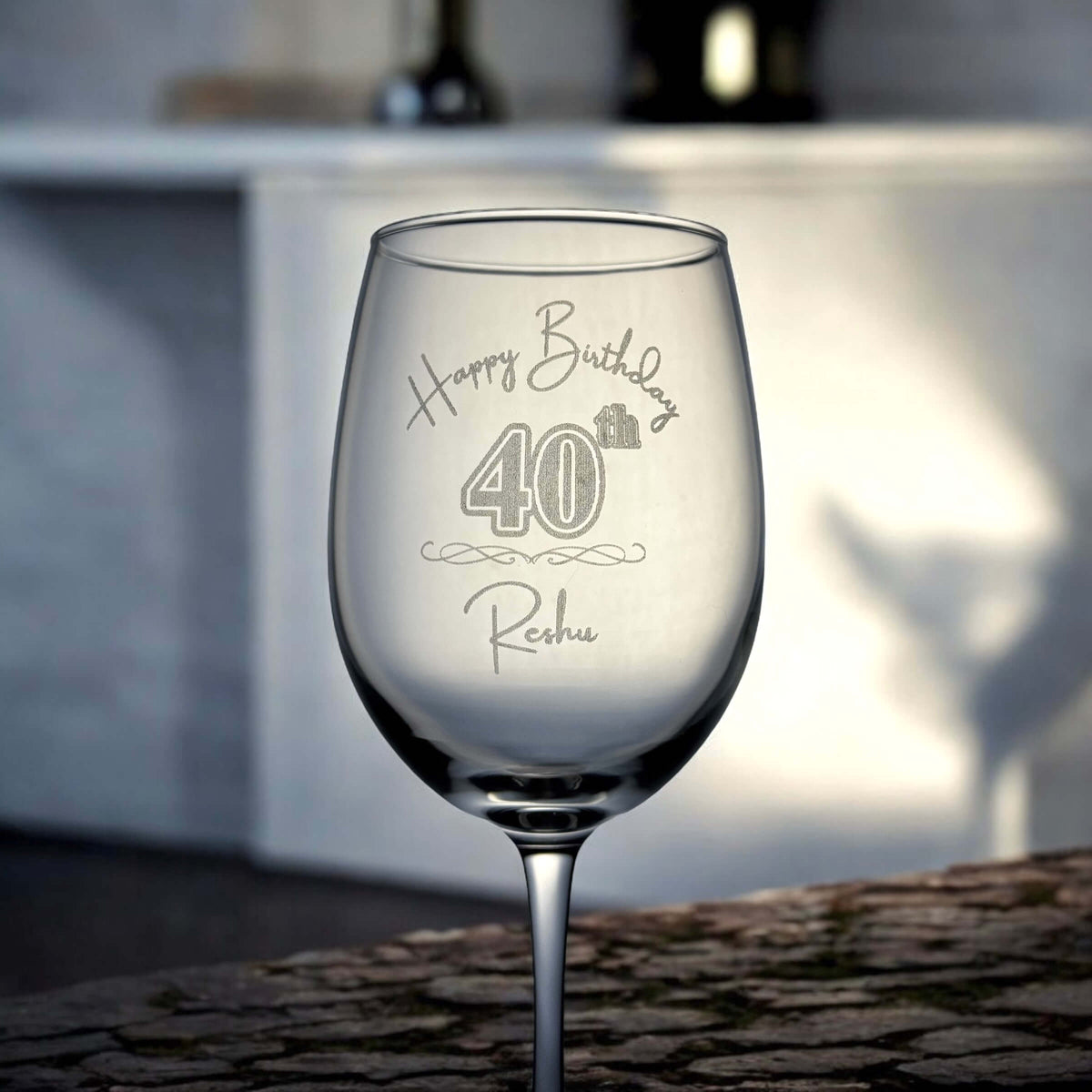 Close-up of engraved wine glass on stone surface with birthday message clearly visible.