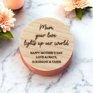 Close-up of engraved wood lid saying “Mum, your love lights up our world”, surrounded by soft blooms