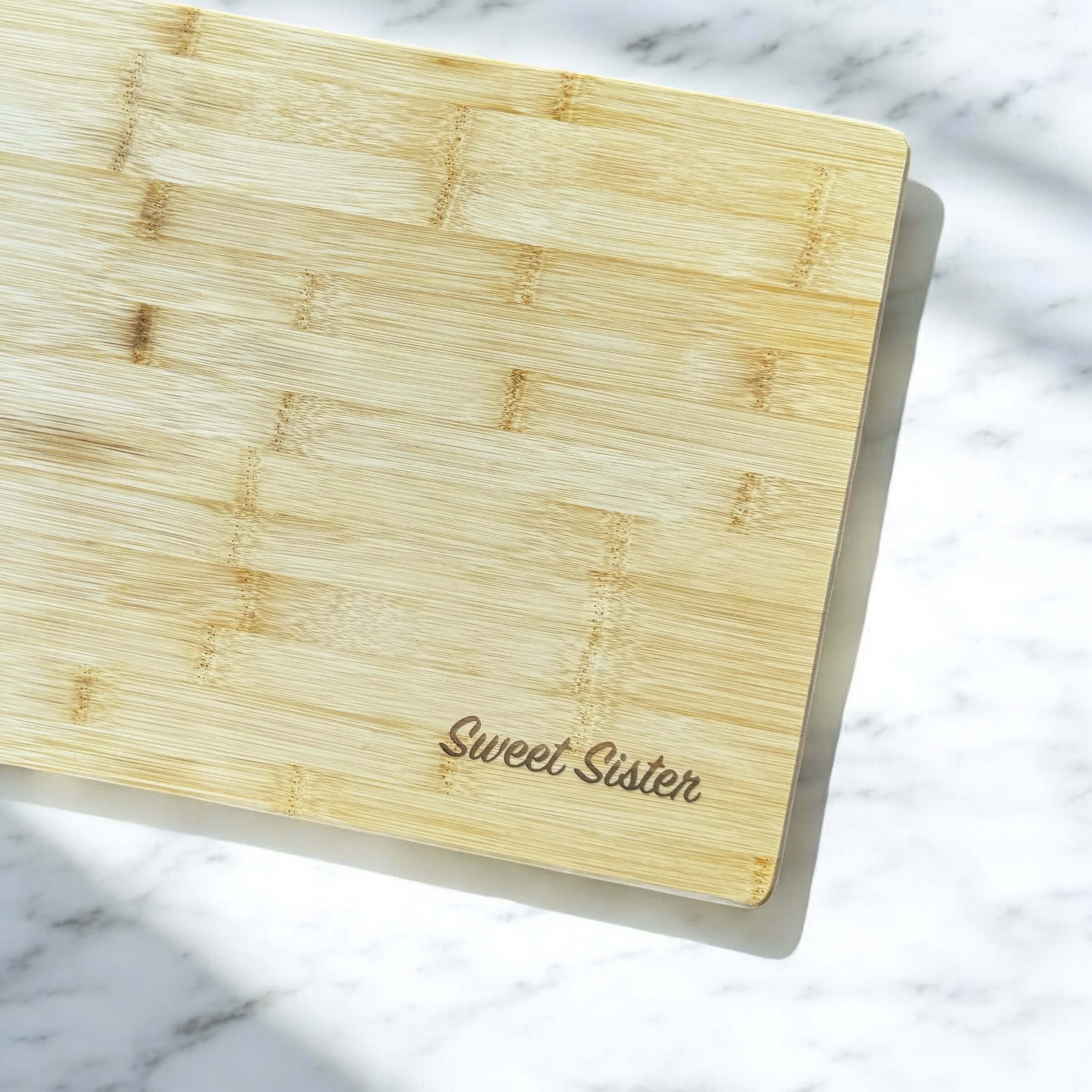 Close-up of laser engraving name on natural bamboo chopping board.