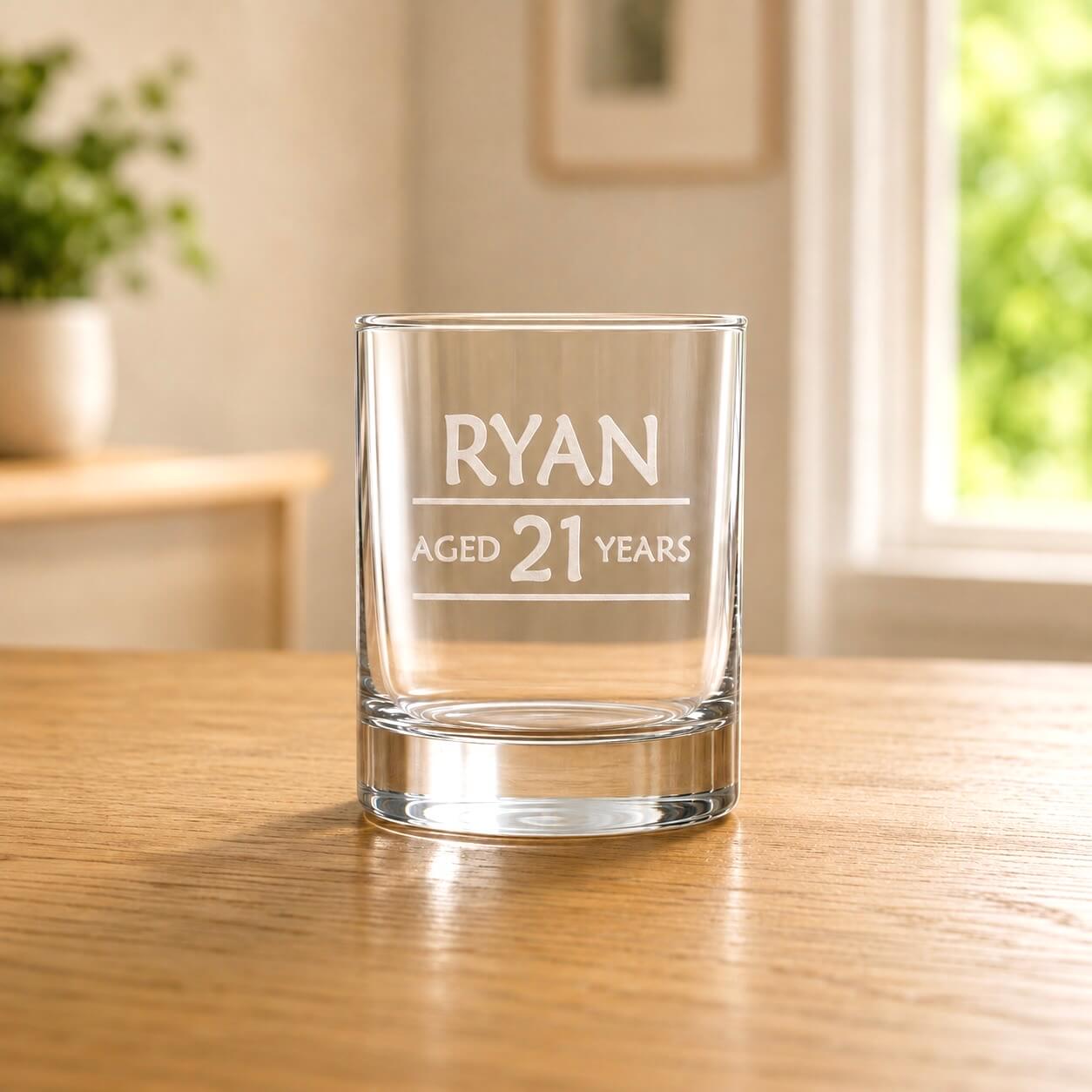 Custom 21st birthday shot glass with frosted Ryan aged 21 engraving on a wooden table