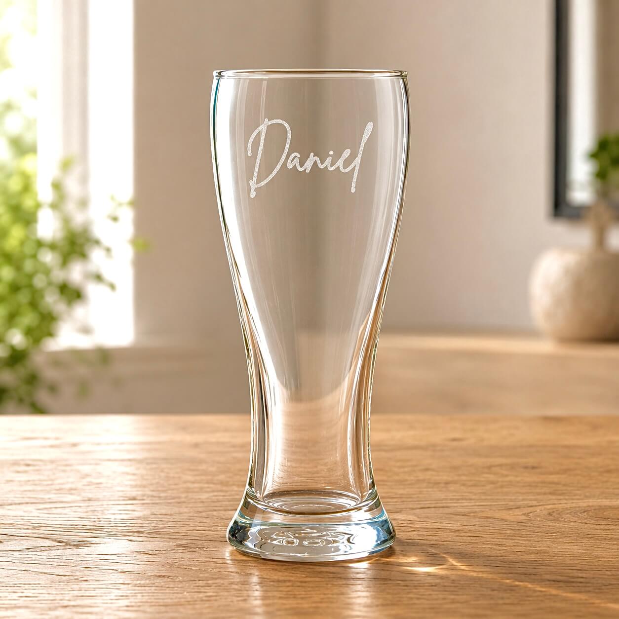 Custom beer glass with Daniel etched on clear pilsner glass on a wooden table
