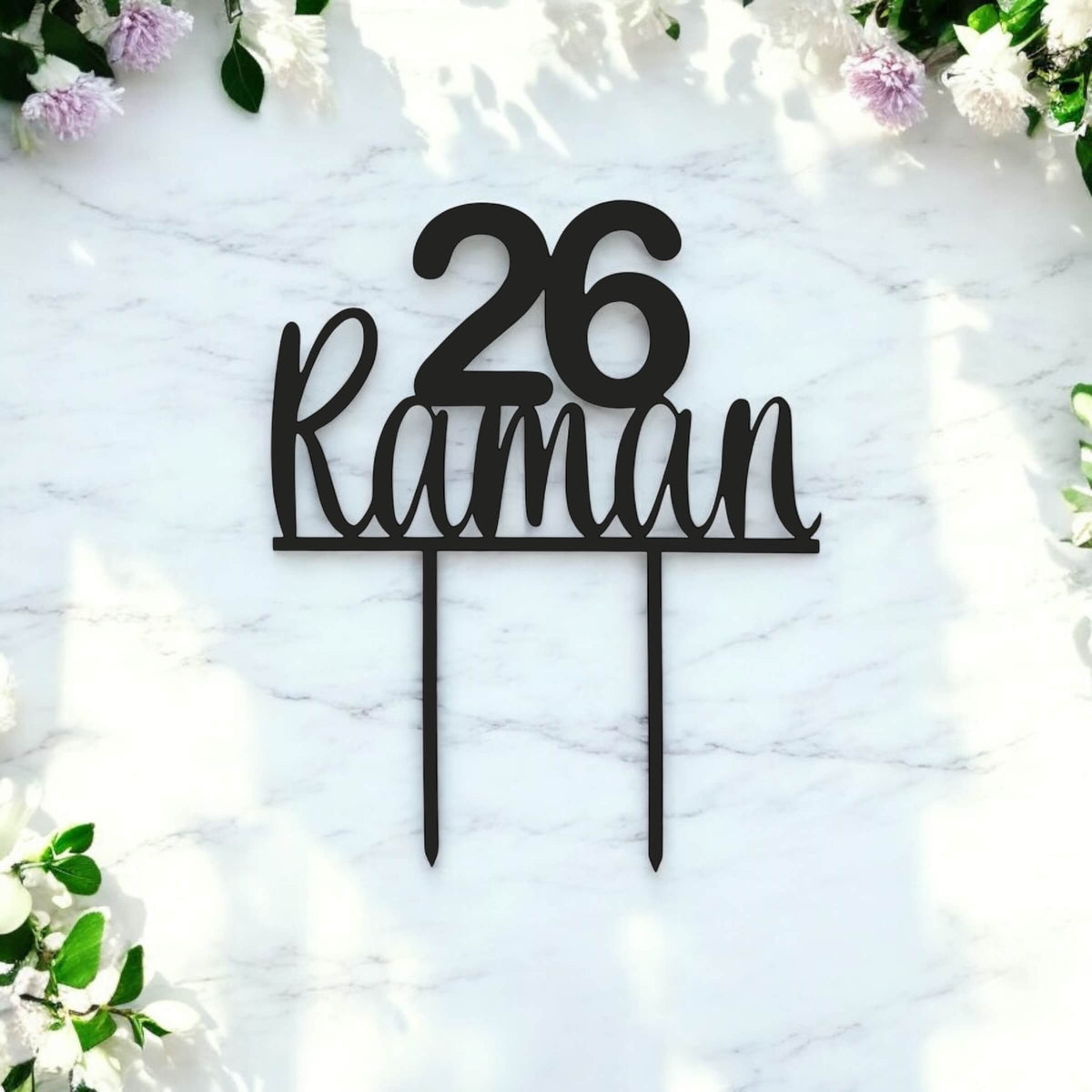 Custom black acrylic age and name topper on white marble background