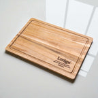 Custom engraved acacia cutting board featuring company branding Lodge, sustainable wooden gift idea for real estate settlements or corporate events.