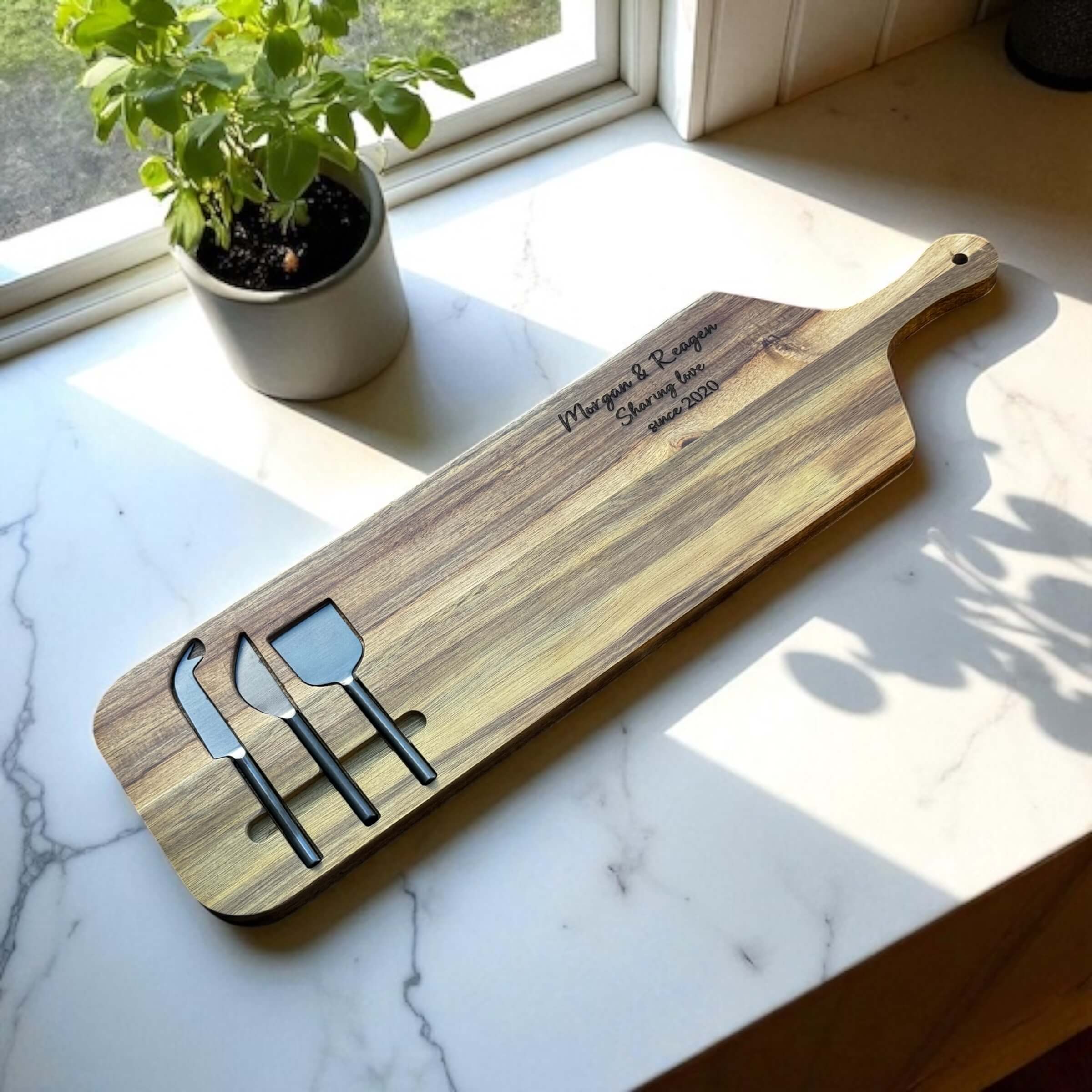 Custom engraved anniversary serving board with cheese knives, displayed in a sunny kitchen setting.