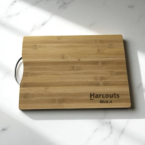 Custom engraved bamboo chopping board featuring company branding, displayed under natural light.