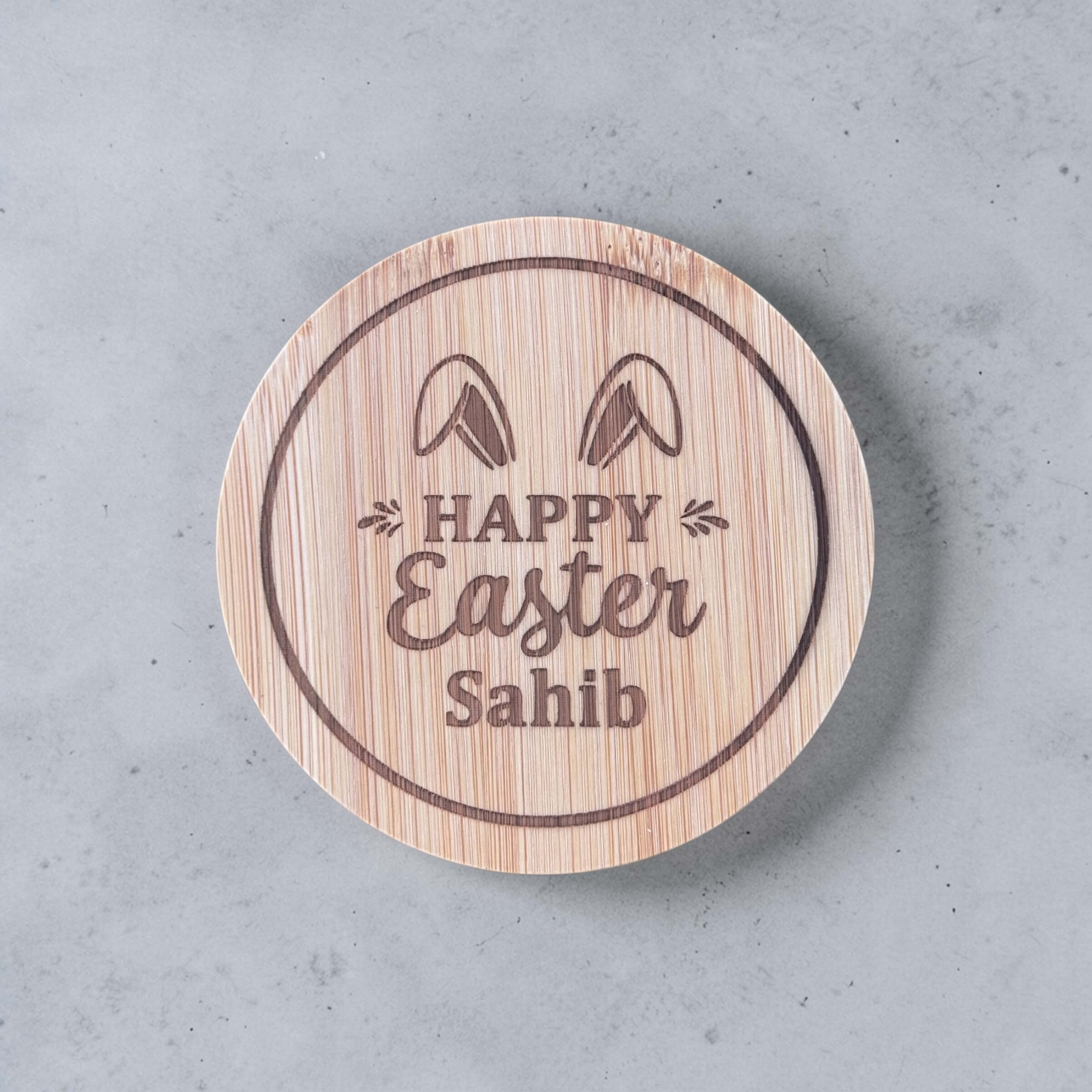 Custom engraved bamboo lid with Happy Easter and personalised name, bunny ears design, round wooden jar lid close up
