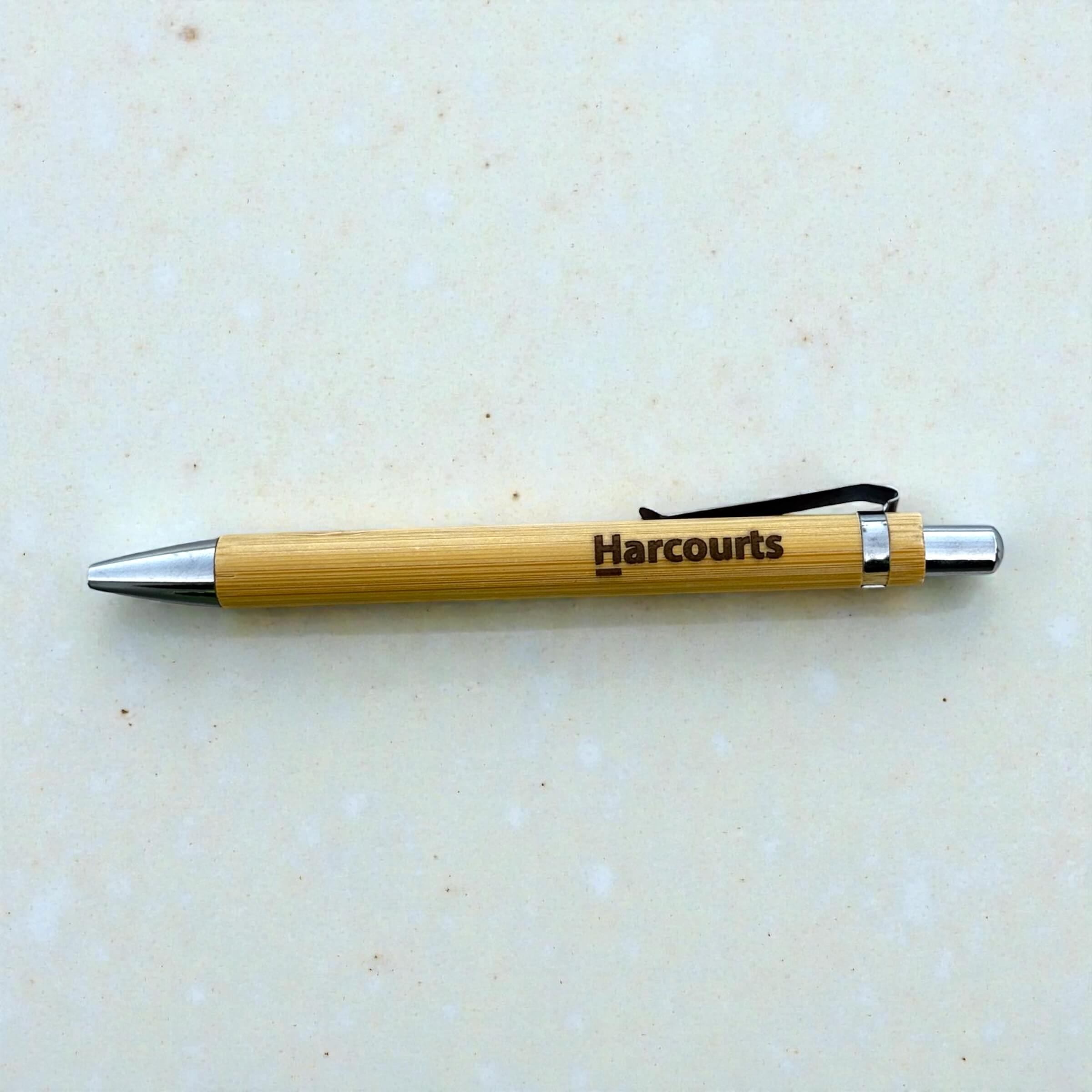 Custom engraved bamboo pen with Harcourts branding, eco-friendly promotional ballpoint pen with chrome accents