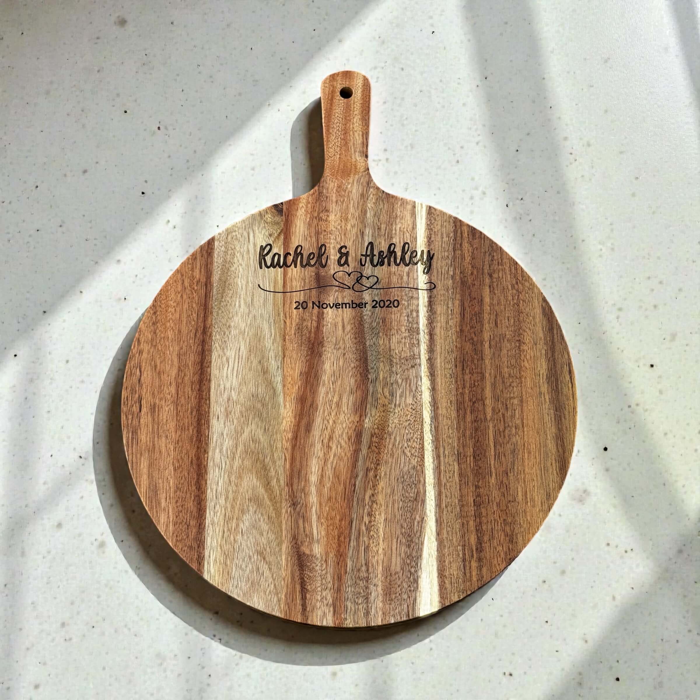 Custom engraved round wooden serve board with couples names Rachel and Ashley and anniversary date, acacia wood with handle