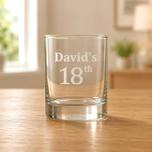 Custom name clear shot glass with frosted 18th birthday etching on a wooden table
