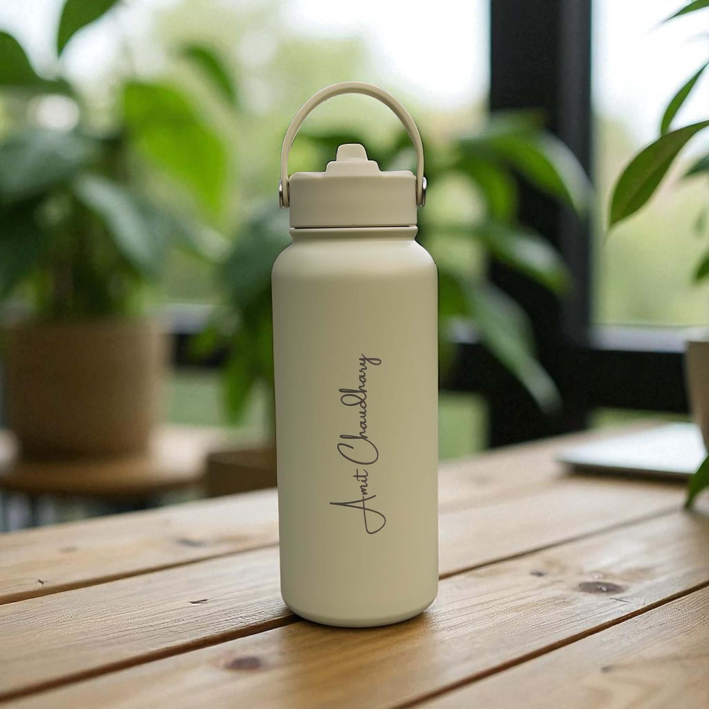 Custom name engraved sage stainless steel water bottle with carry handle, styled in a natural light home setting.