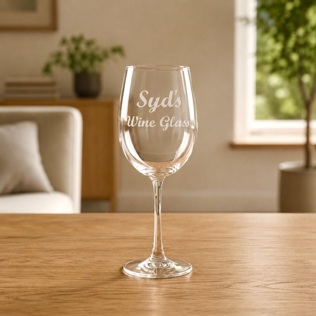 Custom name engraved wine glass personalised with Syd's Wine Glass in elegant script, photographed on a timber table with natural light