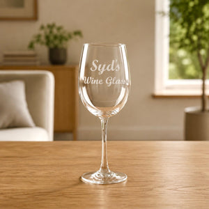 Custom name engraved wine glass personalised with Syd's Wine Glass in elegant script, photographed on a timber table with natural light