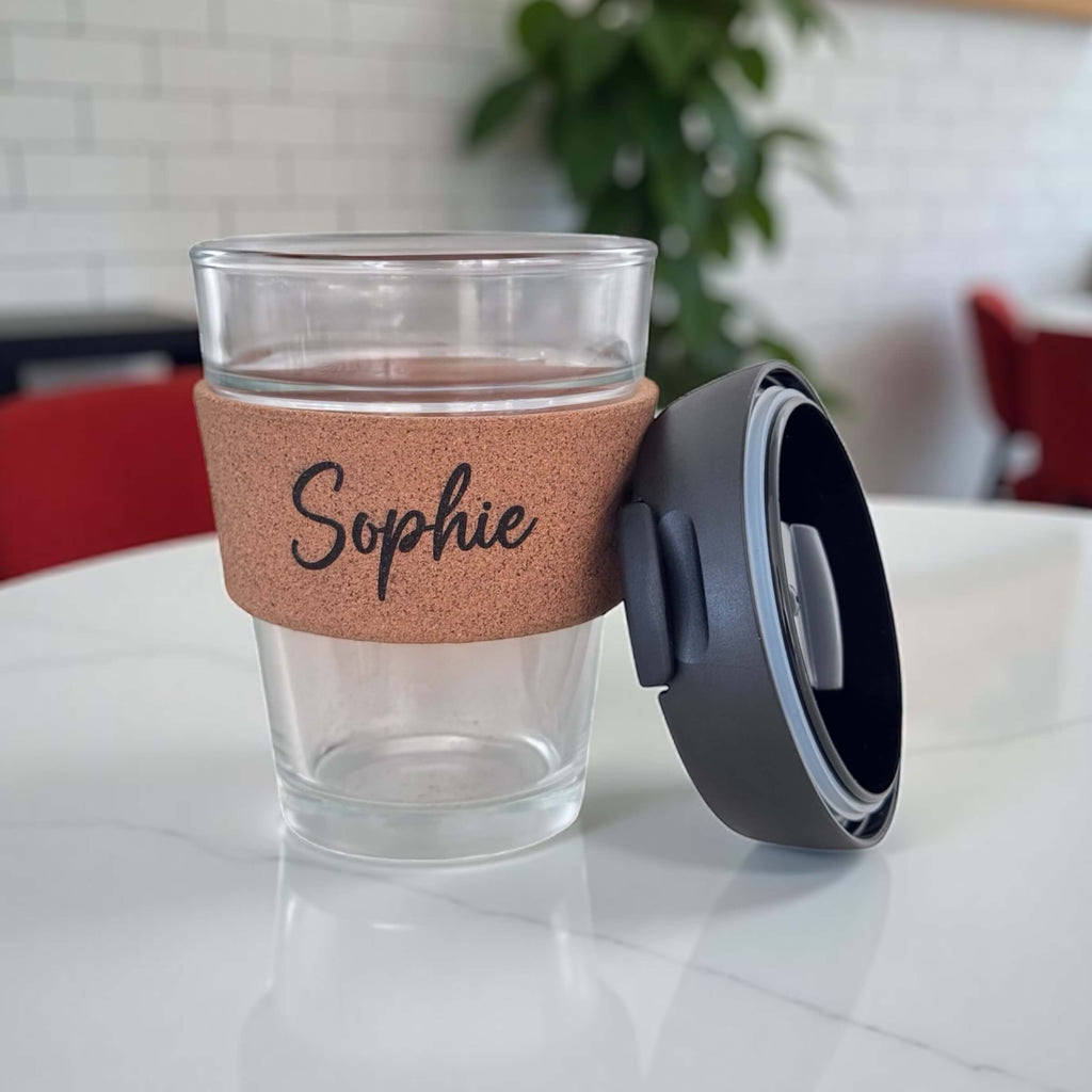 Custom reusable coffee cup with name Sophie and detachable black lid beside the cup