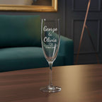 Custom wedding champagne glass engraved “George & Olivia” with heart design and date 27 March 2024 beside lamp