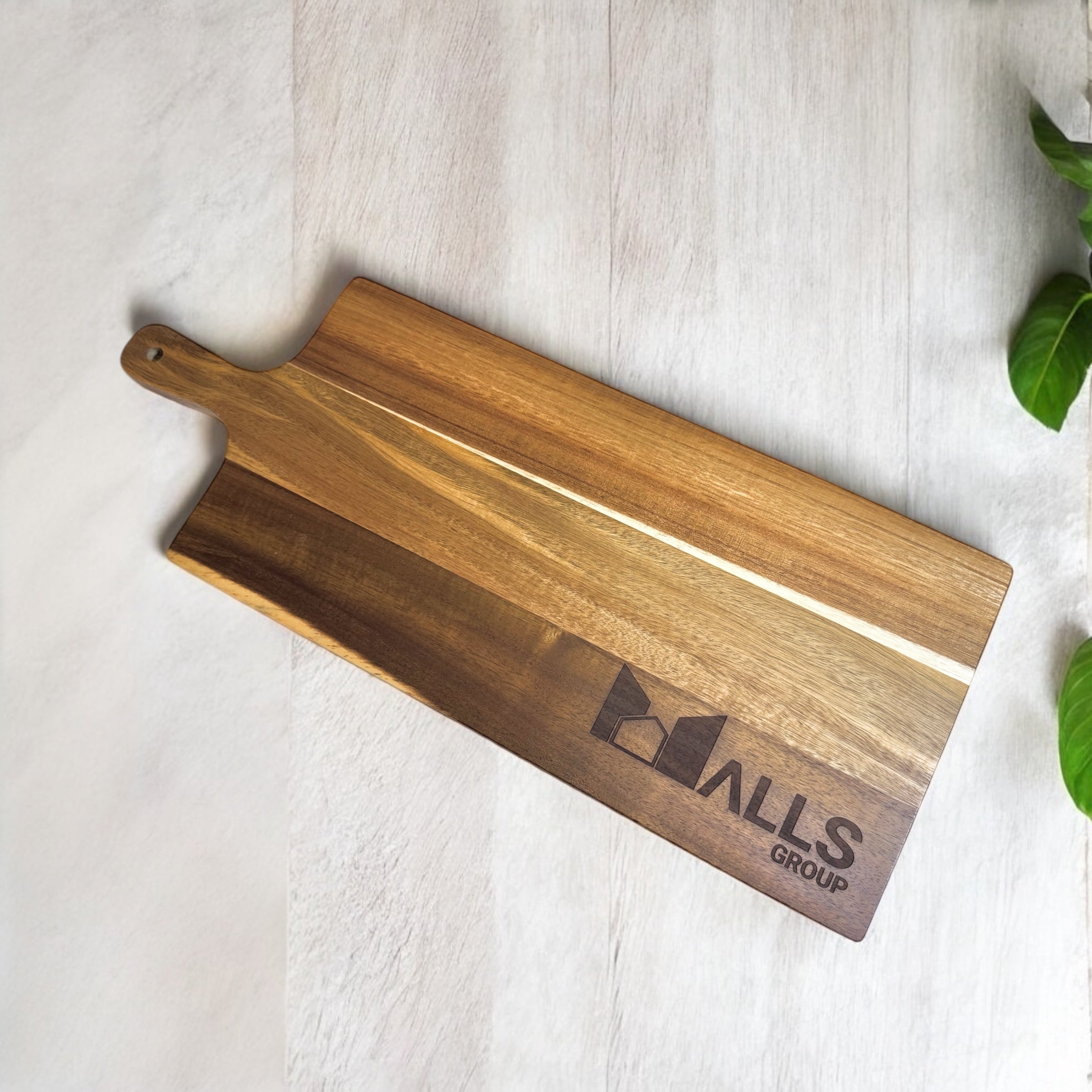 Detail shot of laser-engraved company logo on rich acacia wood paddle board