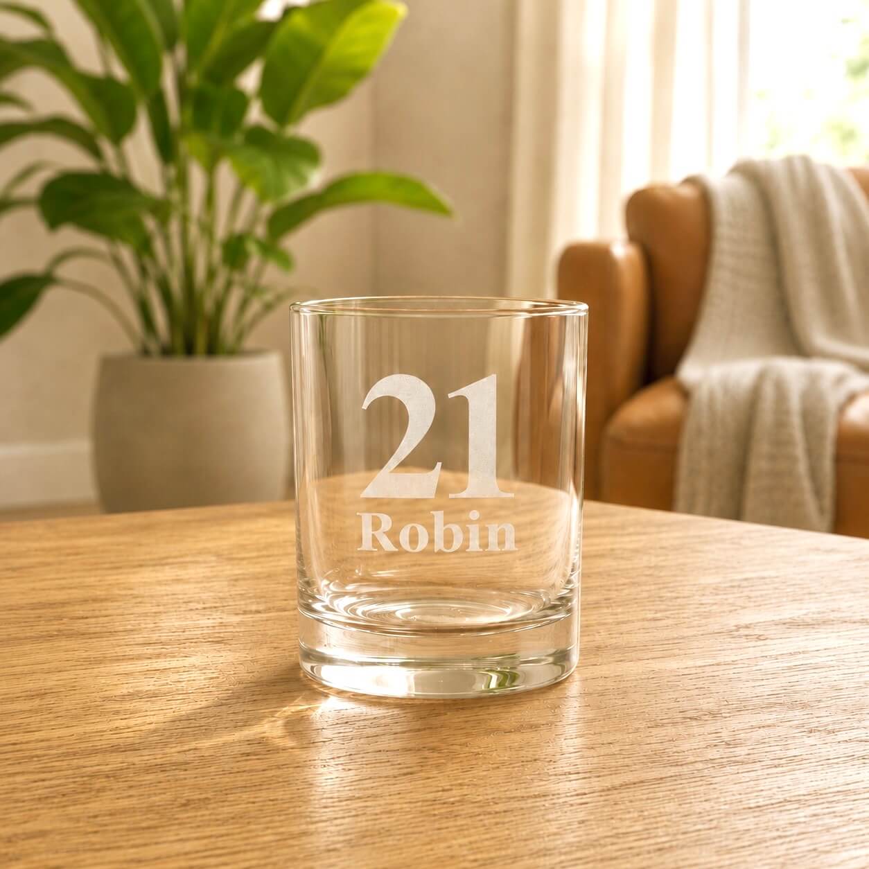 Engraved 21st birthday shot glass in warm light with plant and chair background