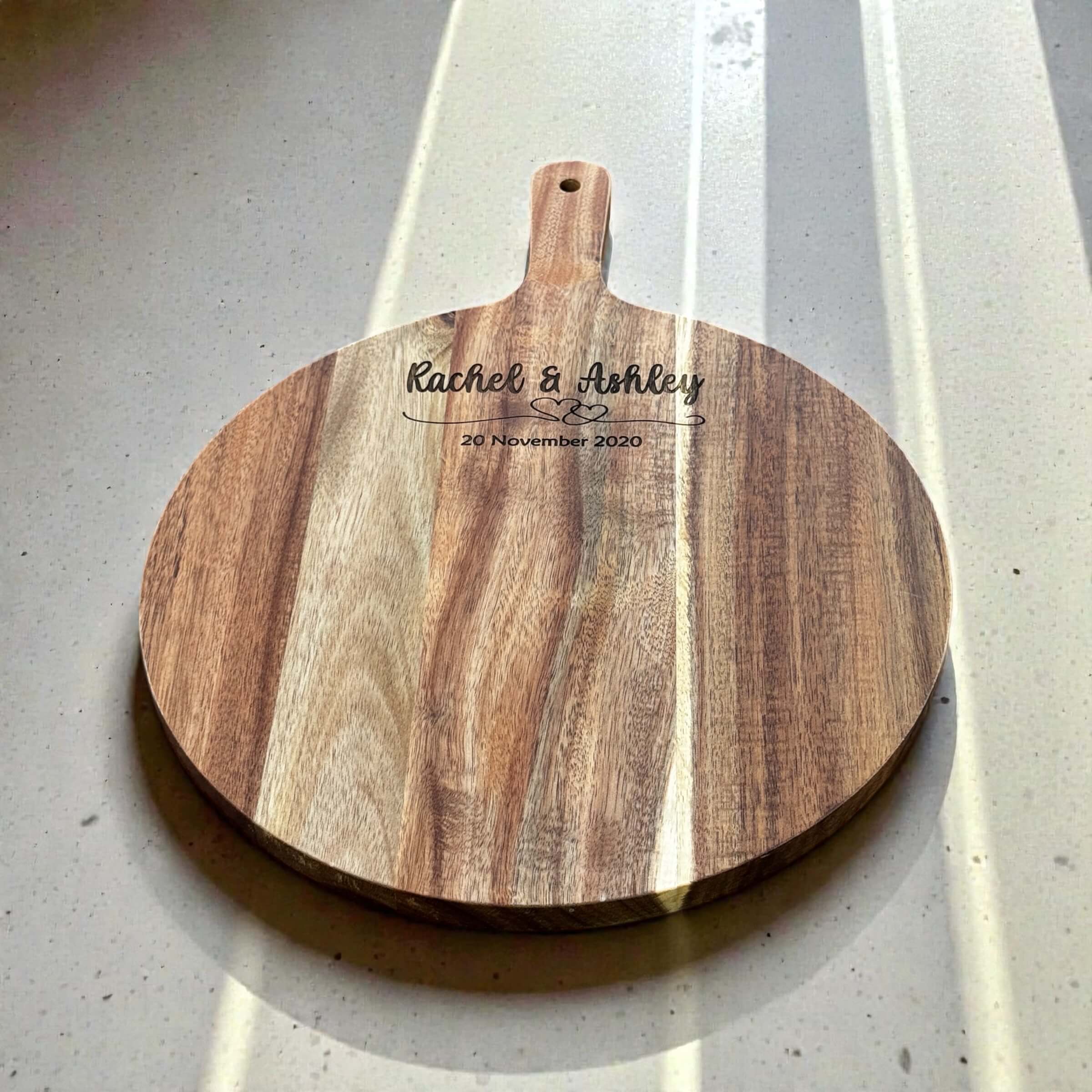 Engraved acacia wood round serving board personalised with couple names and wedding date, unique wedding anniversary gift idea
