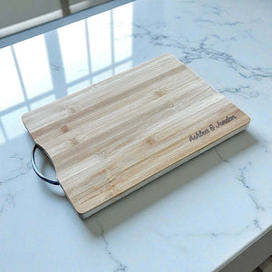 Engraved bamboo board with stainless steel handle in bright kitchen light.