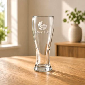 Engraved beer glass with business logo displayed on a wooden table in natural light