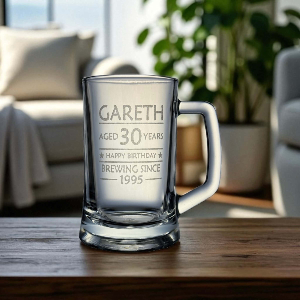Engraved birthday beer mug with the name Gareth and 'Brewing Since 1995' design, set on a wooden table in a relaxed living room with natural light and indoor plants