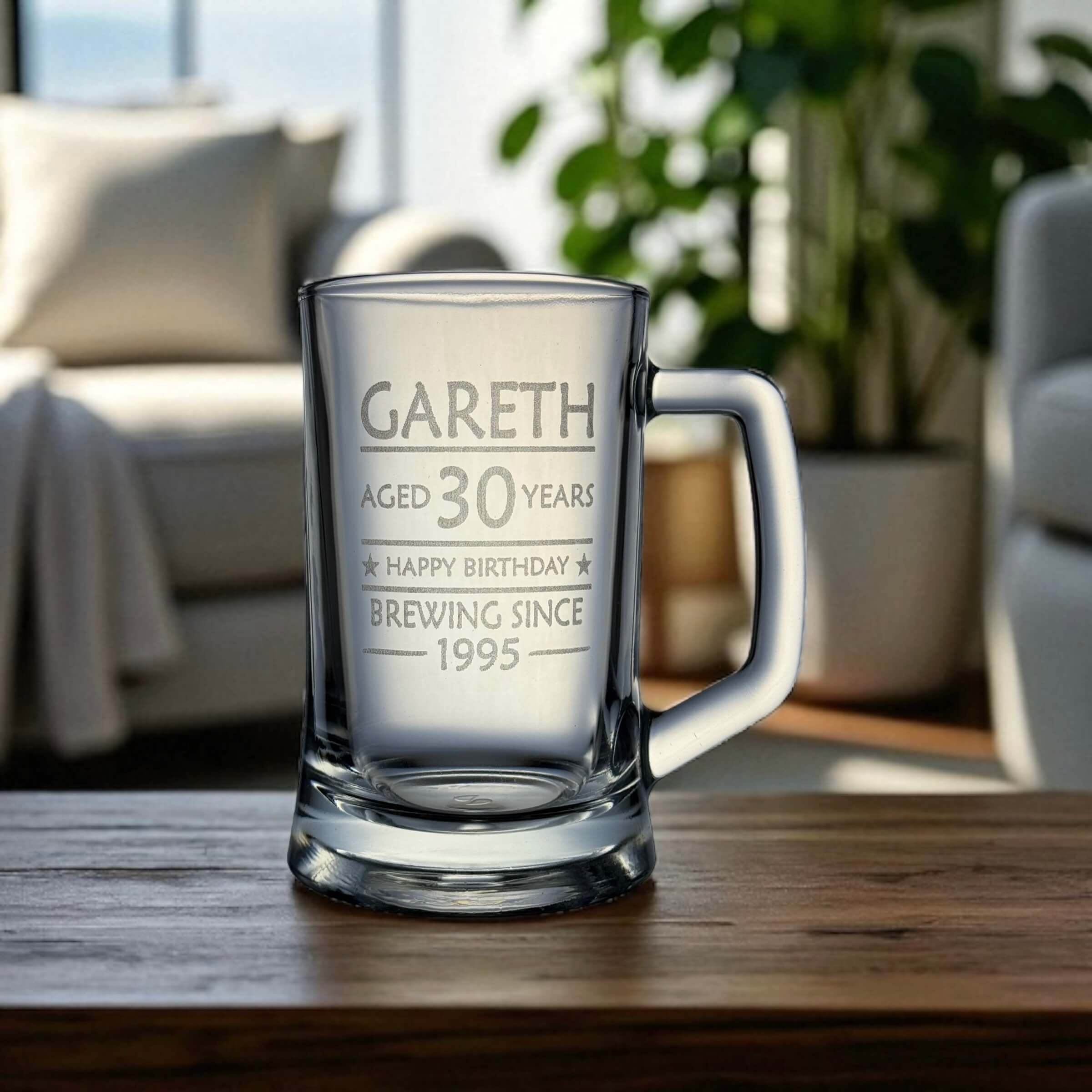 Engraved birthday beer mug with the name Gareth and 'Brewing Since 1995' design, set on a wooden table in a relaxed living room with natural light and indoor plants