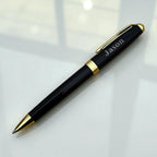 Engraved black and gold pen with name styled under natural light