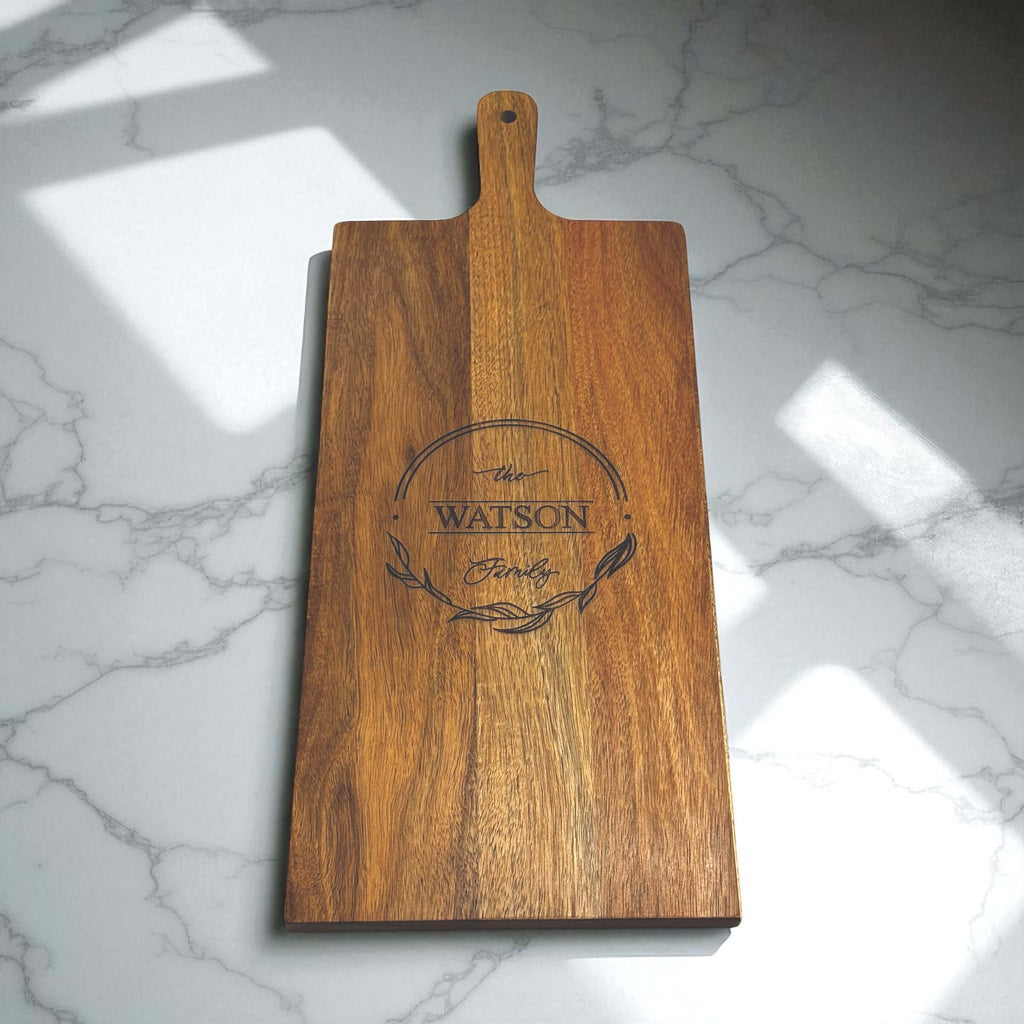 Engraved family serving board with handle, warm wood grain and natural sunlight