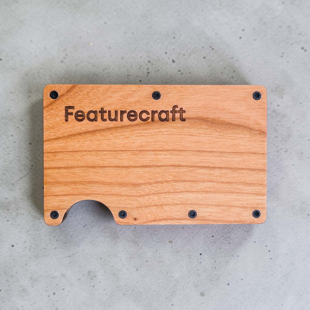 Front view of an engraved business card holder with Featurecraft logo on natural wood grain