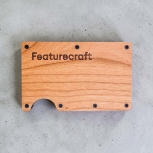 Front view of an engraved business card holder with Featurecraft logo on natural wood grain