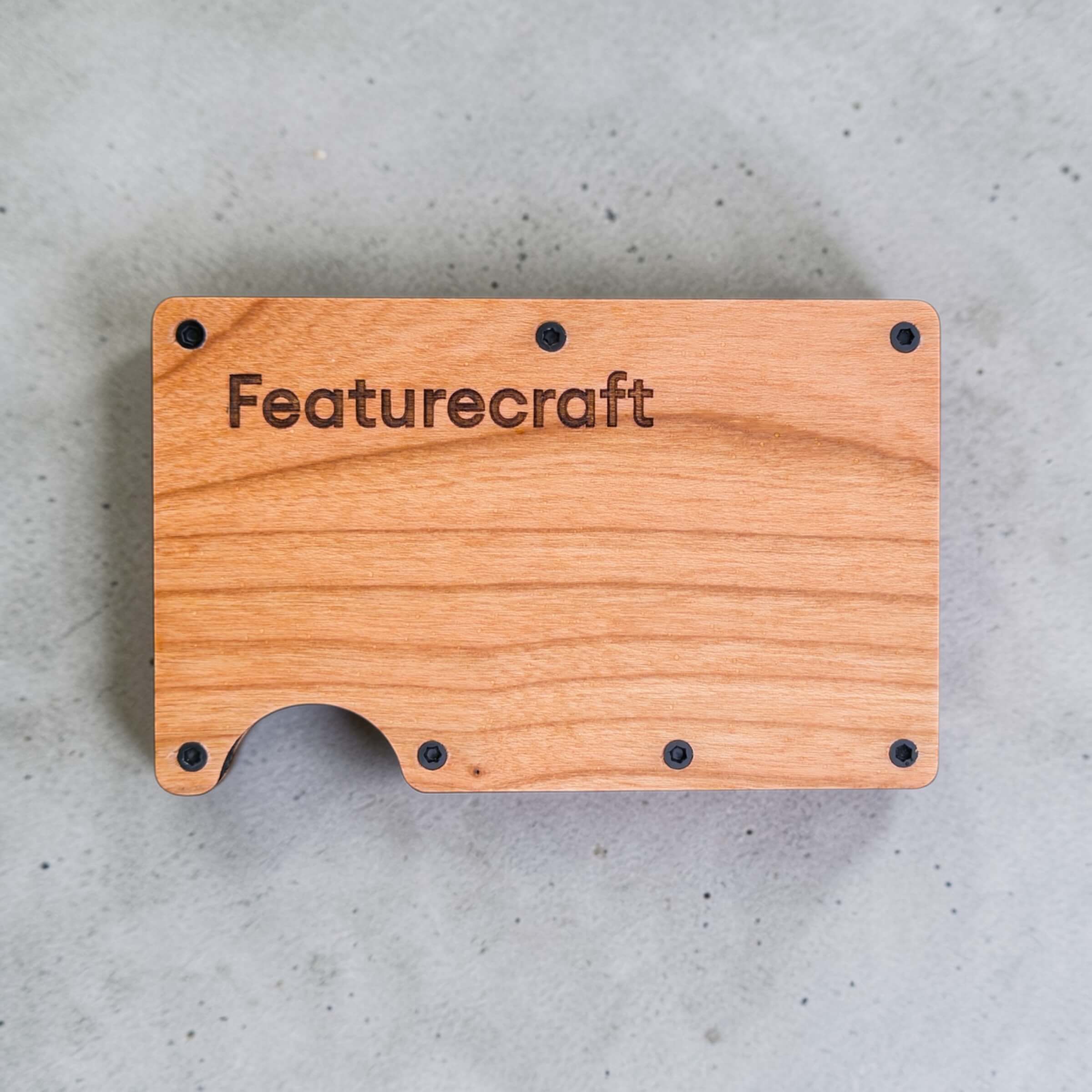 Front view of an engraved business card holder with Featurecraft logo on natural wood grain