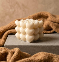 Hand-poured ivory heart cube soy candle with cotton wick on concrete surface, handmade scented bubble candle gift for her