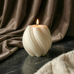 Hand-poured ivory swirl soy candle with cotton wick burning on dark marble surface with velvet backdrop