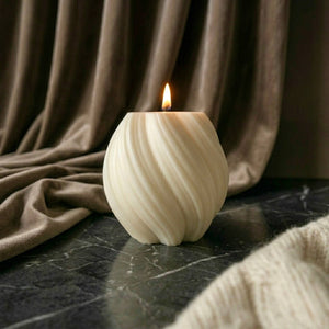Handmade cream swirl ball scented soy candle with cotton wick burning against velvet backdrop