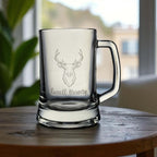 High-quality Pasabahce beer glass with engraved stag and custom name, shown in natural light near a window.