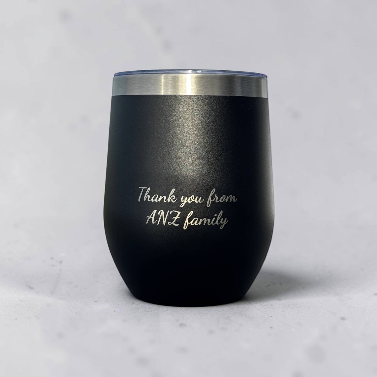 Matte black cup engraved with a script message reading Thank you from ANZ family, an example of a client thank you gift