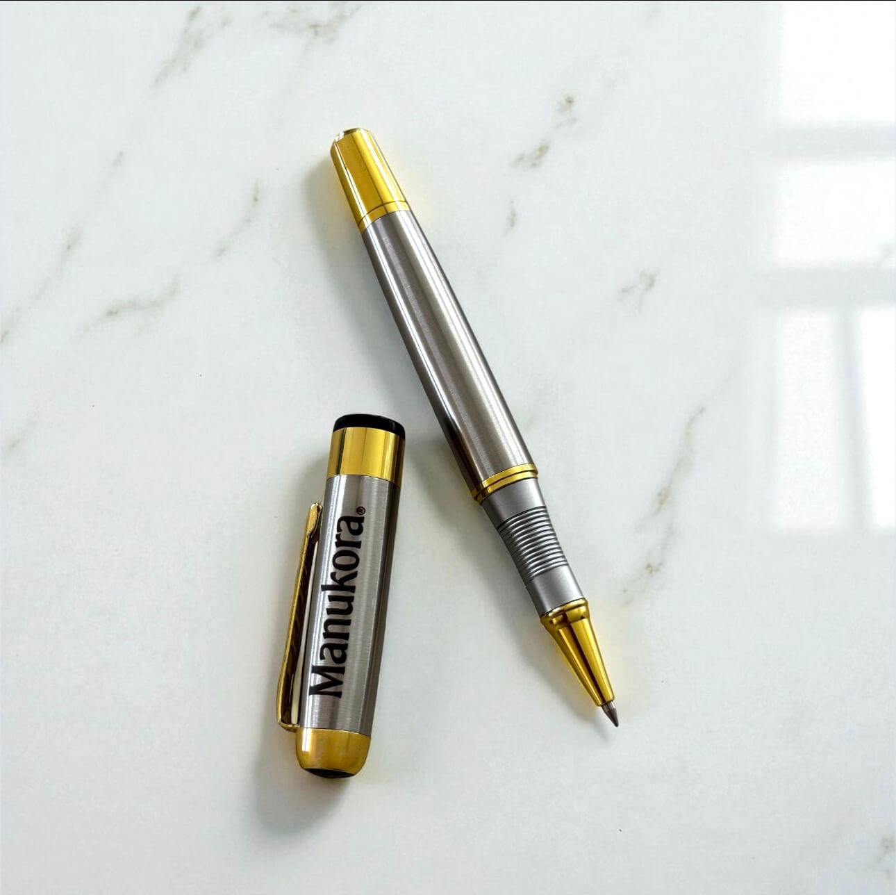 Open engraved roller ball pen with cap off, showing gold detail and fine point nib.