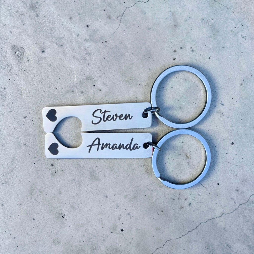 Pair of keychains with engraved names on a concrete surface