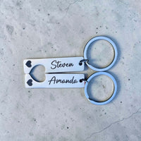 Pair of keychains with engraved names on a concrete surface