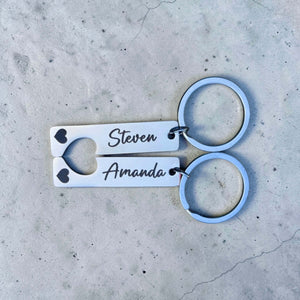 Pair of keychains with engraved names on a concrete surface