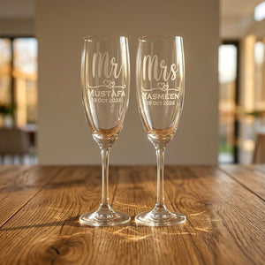 Personalised Mr & Mrs champagne flutes engraved with names Mustafa and Yasmeen and wedding date on a rustic wooden table