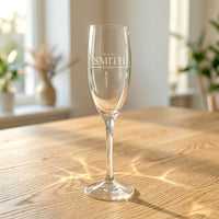 Personalised Mr & Mrs wedding champagne flute engraved with surname Smith, on oak table in sunlit room