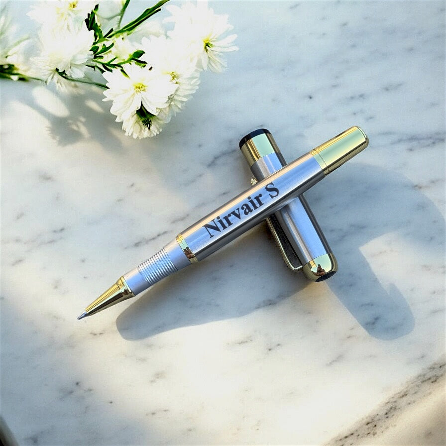Personalised Silver pen with gold accents on a marble surface with white flowers.