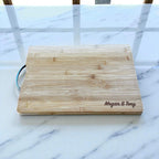 Personalised bamboo chopping board engraved with couple names sitting on a kitchen bench as an anniversary gift