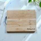 Personalised bamboo chopping board engraved with couple’s names on marble countertop.