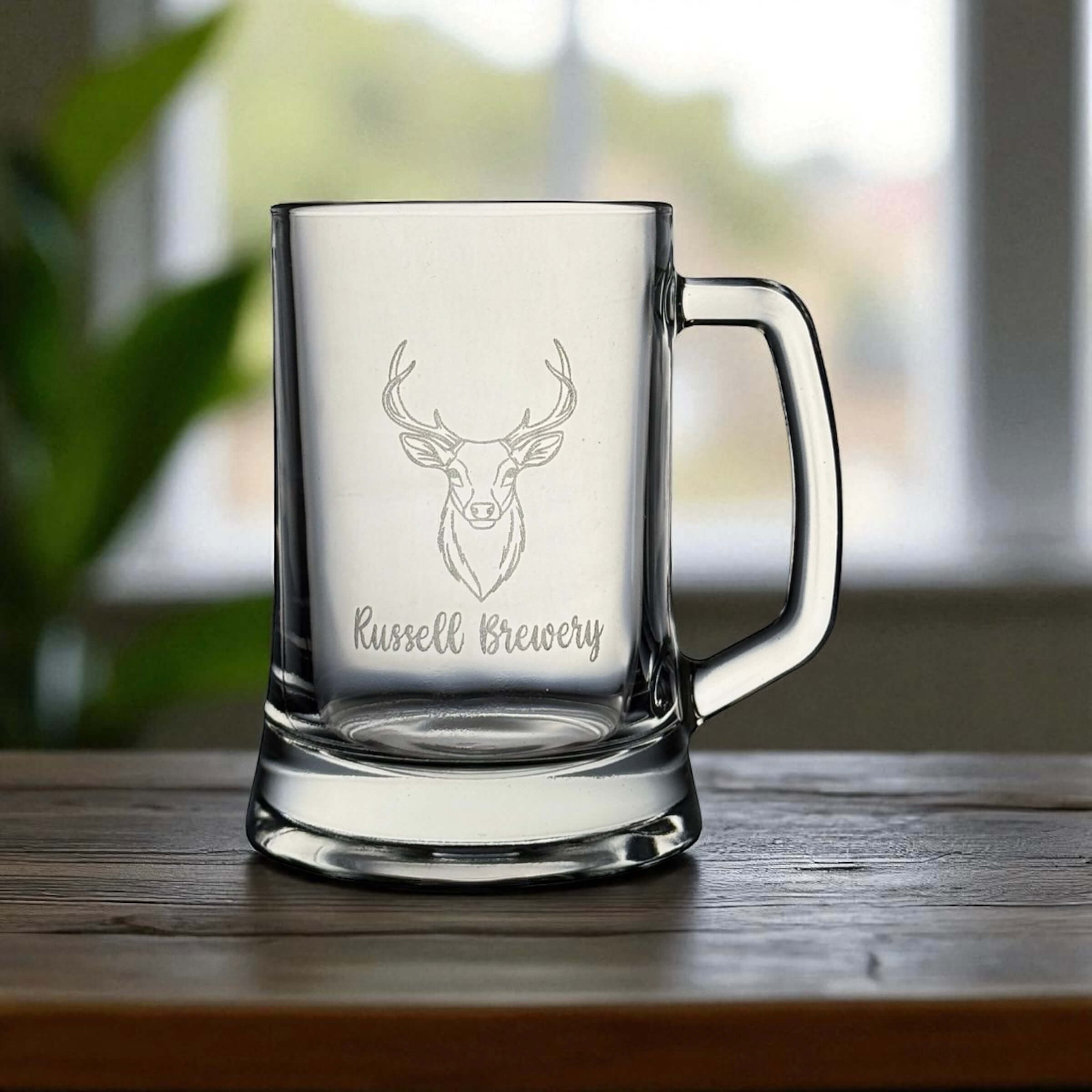 Personalised beer glass featuring stag head engraving and custom name detail, set against a bright window background.