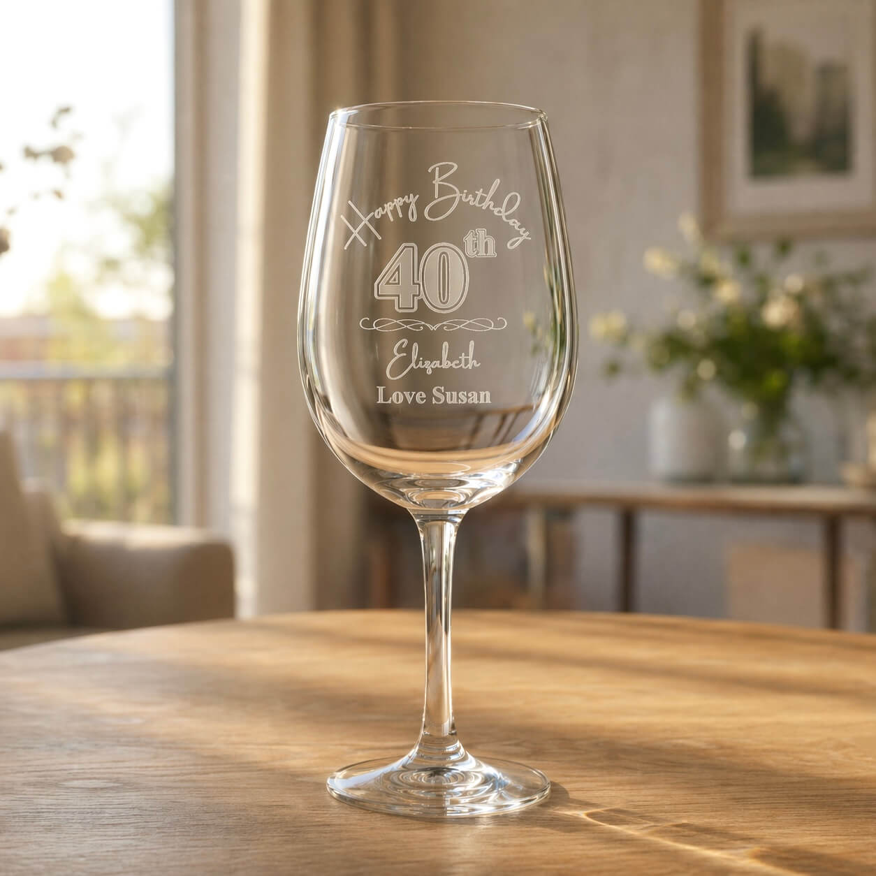 Personalised birthday wine glass engraved with Happy Birthday 40th, Elizabeth, Love Susan, sitting on a wooden dining table in a sunny NZ home